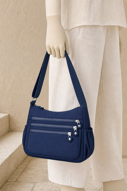 Sac bandoulière femme en tissu Oxford multi-poches — porté à la main en vue rapprochée