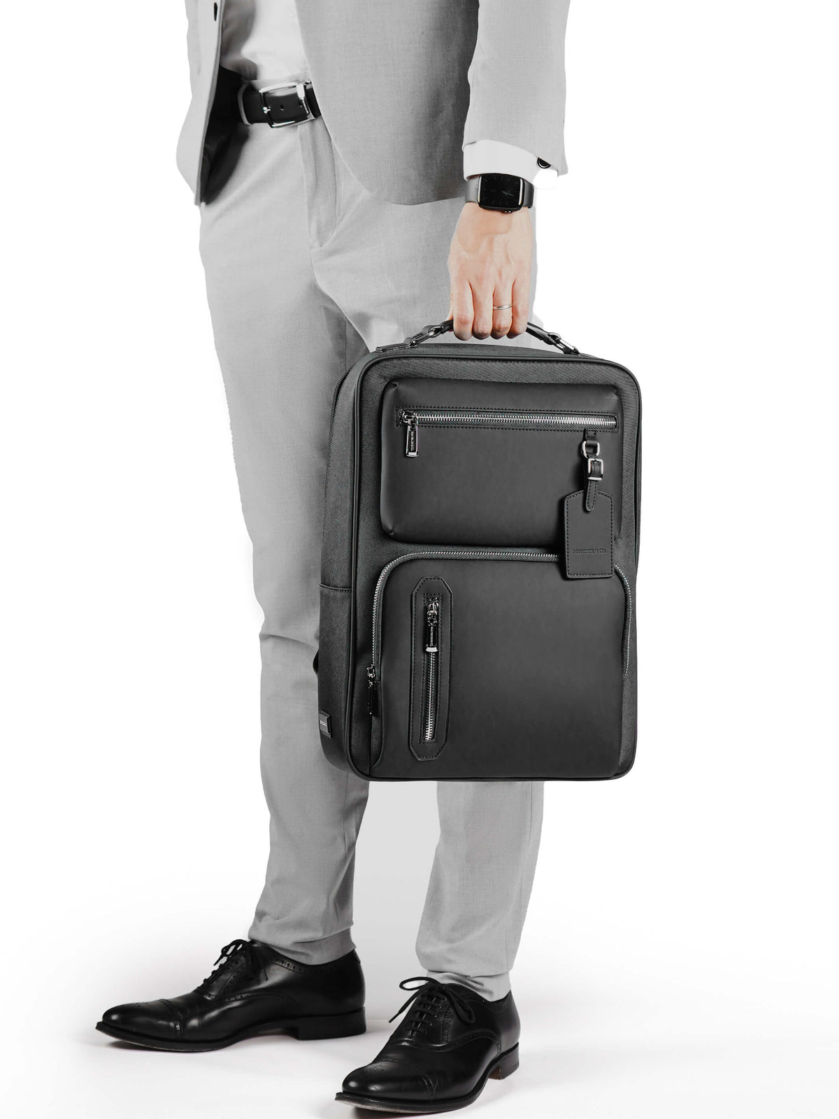 Aurean Paris - Explorer Light Backpack Male model carrying Explorer Light Backpack wearing grey blazer outfit.