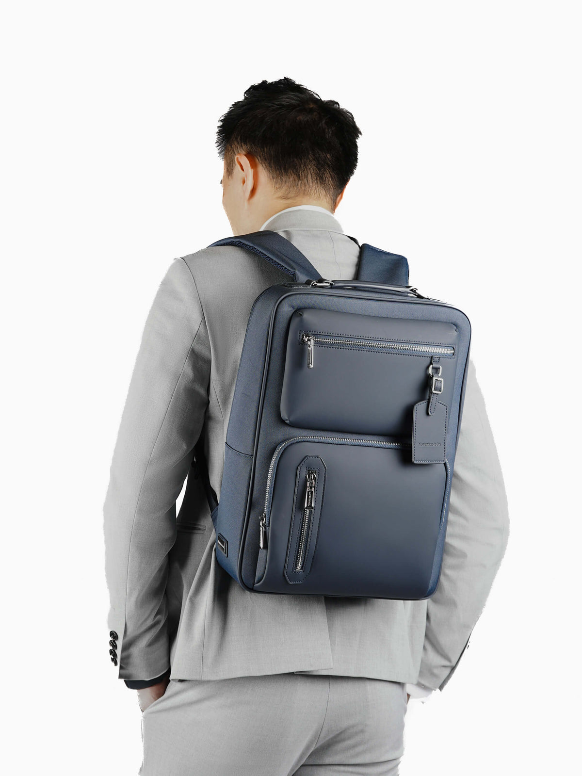 Aurean Paris - Explorer Light Backpack Male model carrying Explorer Light Backpack wearing grey blazer outfit.
