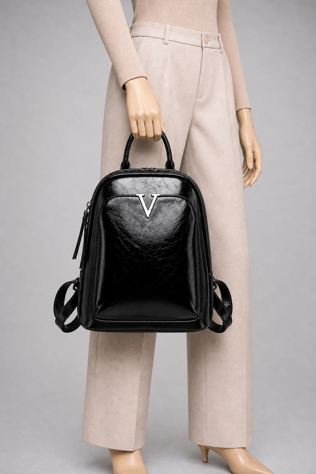 Sac à dos cuir verni femme élégant et imperméable porté à la main en studio - Aurean Paris - source inputs